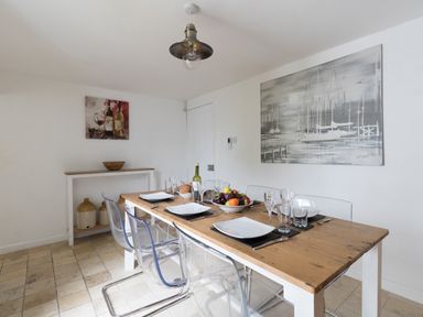 A dining room with a wooden table set for six people and transparent chairs at Fenders Brewers Quay Harbour