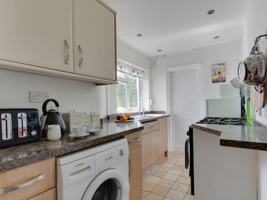A kitchen with a washing machine toaster kettle cups and countertop at Fenders Brewers Quay Harbour