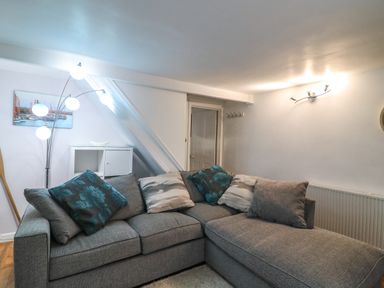 A living room with a gray sectional sofa and floor lamp at Fenders in Brewers Quay Harbour