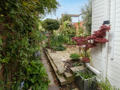 A garden path with plants and trees along a white building at Fenders in Brewers Quay Harbour