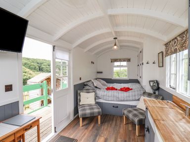 A small living space with a bed two chairs a kitchen countertop sink and door open to outside at Lady Bird Retreat in Skinningrove