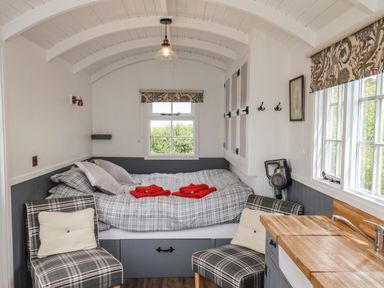 A small bedroom with a built-in bed table chairs and a sink with wooden countertop at Lady Bird Retreat in Skinningrove