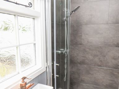 A bathroom with a glass enclosed shower and a window next to a sink with a bronze faucet at Lady Bird Retreat in Skinningrove