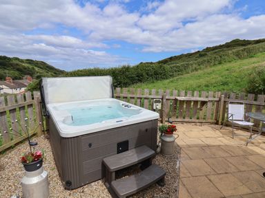 An outdoor patio area with a hot tub fence two chairs and a table at Lady Bird Retreat in Skinningrove