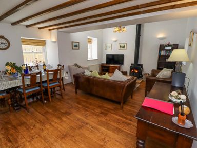 A living room and dining area with wooden floors and exposed ceiling beams at The Coach House in Lowick near Holy Island