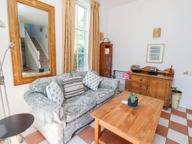 A sitting room with a patterned sofa cushions wooden coffee table wooden sideboard and a large mirror at The Coach House in Lowick near Holy Island