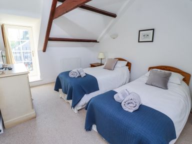 A bedroom with two single beds blue blankets and rolled towels at The Coach House in Lowick near Holy Island