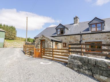 A stone house with dormer windows and wooden fences on a gravel driveway at Yr Hen Stabal in Trawsfynydd