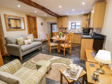 An open plan living area with a kitchen dining table sofa armchair and TV at Yr Hen Stabal in Trawsfynydd
