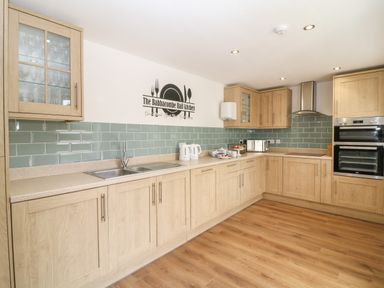 A kitchen with wooden cabinets green tiled backsplash and appliances at Babbacombe Hall in Babbacombe
