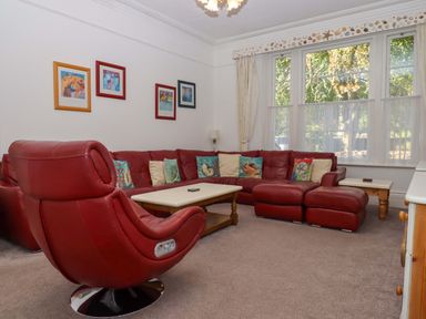 A living room with a red sofa and armchair at Babbacombe Hall in Babbacombe