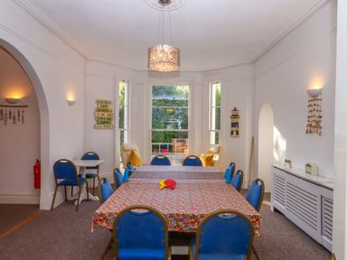 A dining room with a table and blue chairs at Babbacombe Hall in Babbacombe
