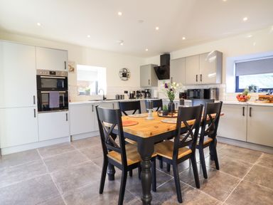 A kitchen with gray cabinets wooden dining table and black chairs at Tyn Llwyn Barn in Glyndyfrdwy near Llangollen