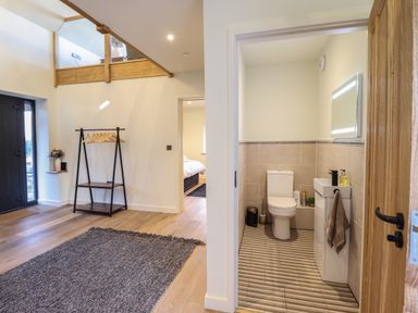 An entryway with a coat rack and a bathroom with a toilet and sink at Tyn Llwyn Barn in Glyndyfrdwy near Llangollen