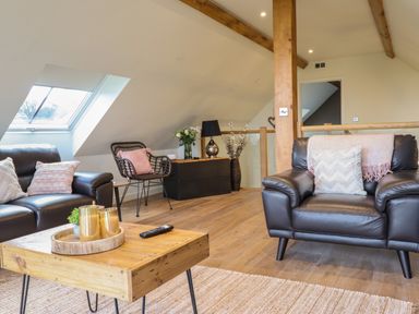 A sitting area with leather armchairs a wicker chair wooden coffee table and skylight windows at Tyn Llwyn Barn in Glyndyfrdwy near Llangollen