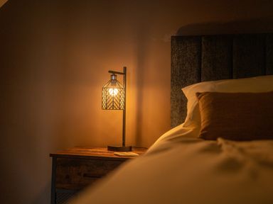 A bedside table with a lamp and a book next to a bed at Tyn Llwyn Barn in Glyndyfrdwy near Llangollen
