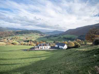 A rural landscape with two white houses surrounded by fields and hills at Tyn Llwyn Barn in Glyndyfrdwy near Llangollen