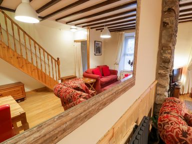 A living room with red sofas wooden stairs a large mirror and a television at Edrydd in Harlech