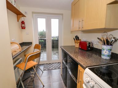 A kitchen with countertop appliances stools and a glass door leading outside at Edrydd in Harlech