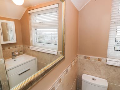A bathroom with a sink cabinet mirror window blinds and toilet at Edrydd in Harlech