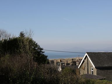 A coastal view with houses trees and hills near the sea at Edrydd in Harlech