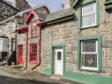 Stone cottages with red and green window frames and doors on a narrow street at Edrydd in Harlech