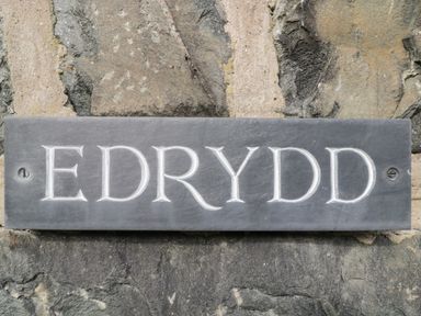 A carved stone nameplate reading Edrydd mounted on a stone wall at Edrydd in Harlech