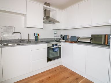A kitchen with white cabinets a sink stove oven and various kitchen appliances on the counter at Onshore 7 in Newquay