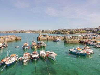 A harbor with multiple small boats anchored in the water and buildings in the background at Onshore 7 in Newquay