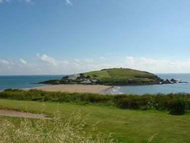 A coastal scene with green grass foreground sandy beach and houses on a hill by the sea at Duffield in St Ann's Chapel