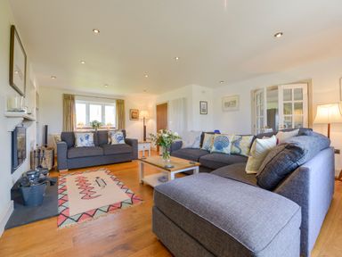 A living room with grey sofas a wooden coffee table and a window with curtains at Duffield in St Ann's Chapel