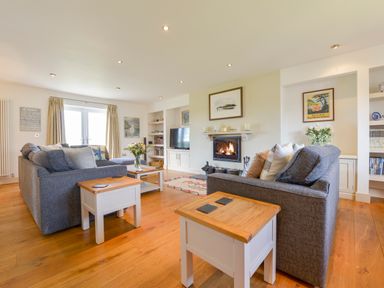 A living room with two gray sofas and wooden side tables near a fireplace and a television at Duffield in St Ann's Chapel