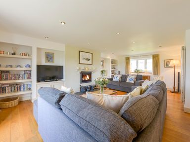 A living room with gray sofas a wooden coffee table a television a fireplace and shelves with books and decorative items at Duffield in St Ann's Chapel
