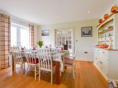 A dining room with a table set for a meal six chairs wooden floor and a cupboard with dishes at Duffield in St Ann's Chapel