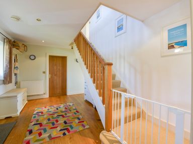A hallway with wooden staircase and a colorful rug on the floor at Duffield in St Ann's Chapel