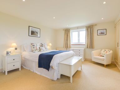 A bedroom with a bed bedside tables lamps a chest of drawers and an armchair at Duffield in St Ann's Chapel