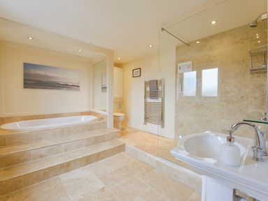 A bathroom with a bathtub on a raised platform steps shower area sink and toilet at Duffield in St Ann's Chapel