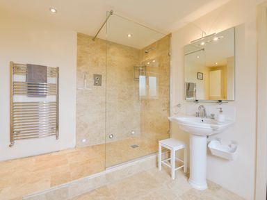 A bathroom with a walk in shower a white pedestal sink a mirror and a heated towel rail at Duffield in St Ann's Chapel