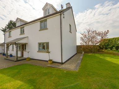 A white two-story house with green windows and a wooden porch surrounded by a lawn and small trees at Duffield in St Ann's Chapel