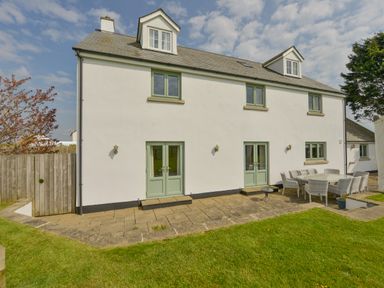The exterior of a two-story white house with green doors and windows and an outdoor dining table with chairs at Duffield in St Ann's Chapel