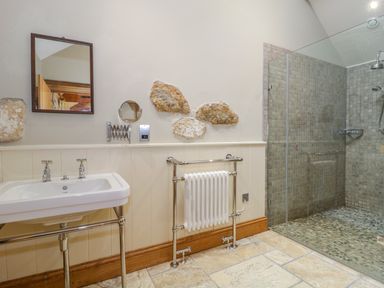 A bathroom with a sink radiator stone decorations and a glass shower at Middle Farm Annex in Long Bredy