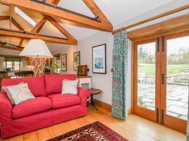 A living room with a red sofa and wooden beams at Middle Farm Annex in Long Bredy