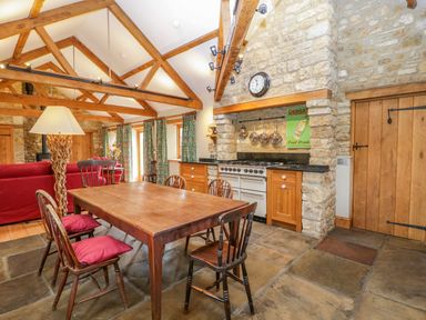 A kitchen and dining area with wooden table and chairs stone walls and a stove at Middle Farm Annex in Long Bredy