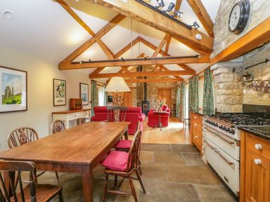 A kitchen and dining area with wooden table and chairs next to a stove and living room at Middle Farm Annex in Long Bredy