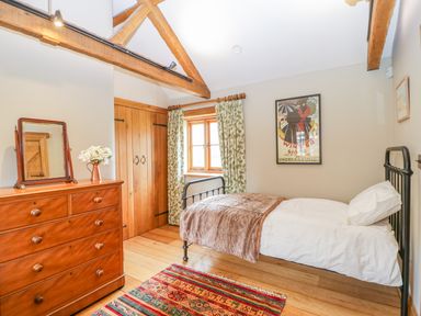 A bedroom with a single bed wooden wardrobe floral curtains and a chest of drawers at Middle Farm Annex in Long Bredy