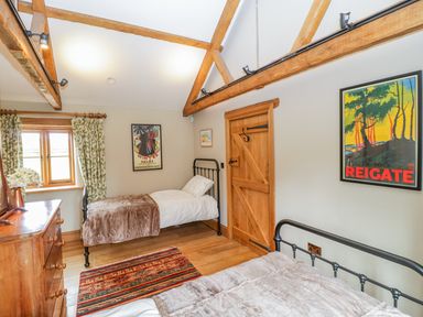 A bedroom with two single beds a wooden dresser a window with floral curtains a door and framed artwork at Middle Farm Annex in Long Bredy