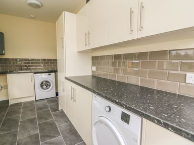 A utility room with washing machines under black countertops and white cabinets at New Peny in Llandrindod Wells