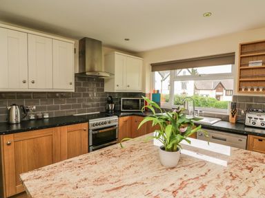A kitchen with wooden and white cabinets a stove microwave toaster sink window and a plant on a countertop at New Peny in Llandrindod Wells