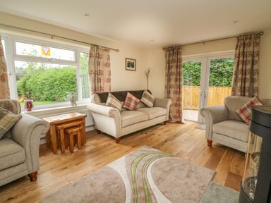 A living room with sofas and a rug near windows and glass doors at New Peny in Llandrindod Wells