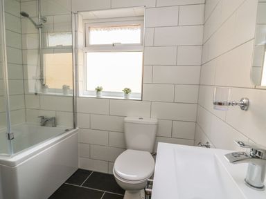 A bathroom with a bathtub shower combination toilet and sink with window above at New Peny in Llandrindod Wells